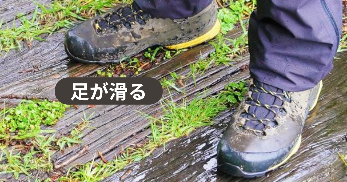 雨に濡れた木道に立つ登山者、雨の日は足が滑る